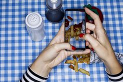 Snapping a mobile photo of french fries on a blue checkered table