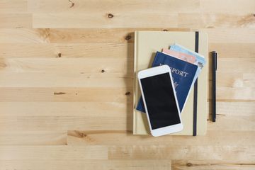 Phone on passport and notebook next to pen