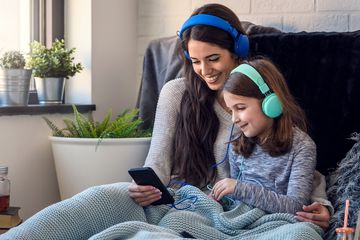 A woman and her daughter wearing headphones and listening to music on an Apple iPhone.