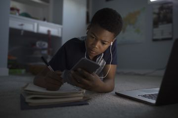 An image of a child looking at his smartphone while studying.