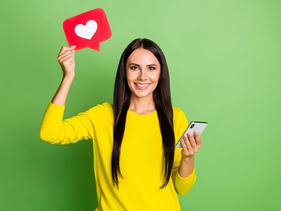 A woman with a smartphone holding up a heart icon