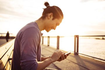 Remote Worker Using Smartphone In Park At Sunset