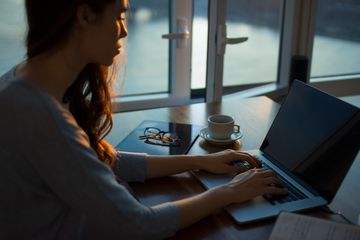 Woman working on laptop computer in dim room.