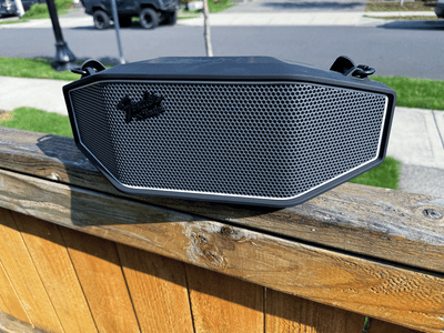 Fender x Teufel Rockster Cross Bluetooth speaker on a fence outside