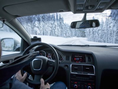 Person driving SUV in snow covered road in a forest