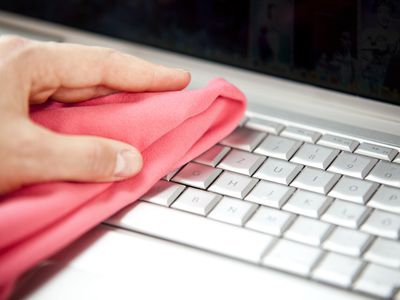 Cleaning laptop keyboard with cloth.