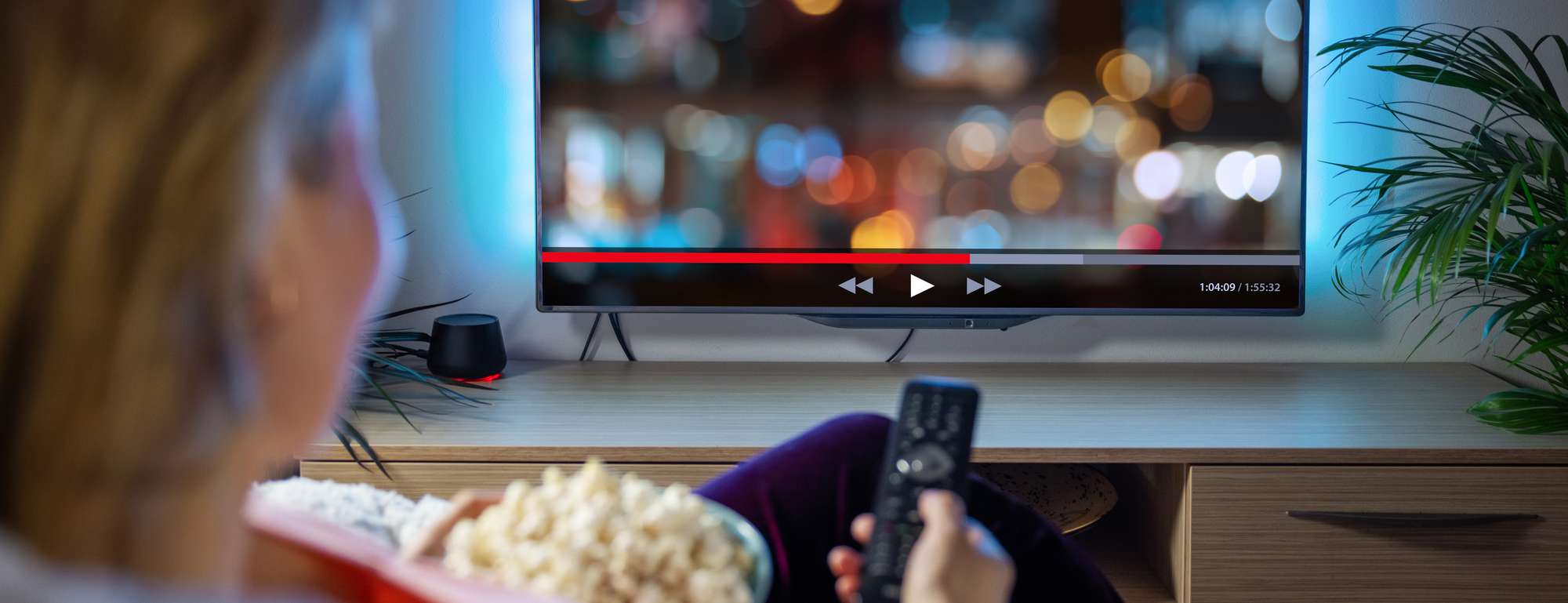 Woman streaming shows on TV with popcorn and remote in hand