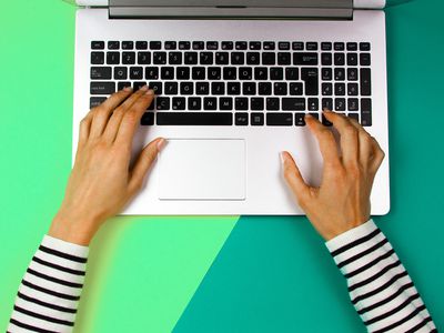 Cropped hands of woman using laptop over colored background