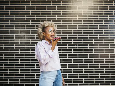 A woman standing in front of a wall, using her speakerphone