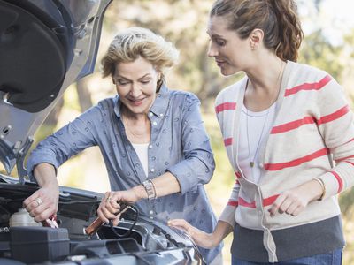 Two women jumpstarting a car battery