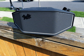 Fender x Teufel Rockster Cross Bluetooth speaker on a fence outside