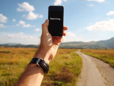 A man holding a smartphone while searching for a cellular network signal.