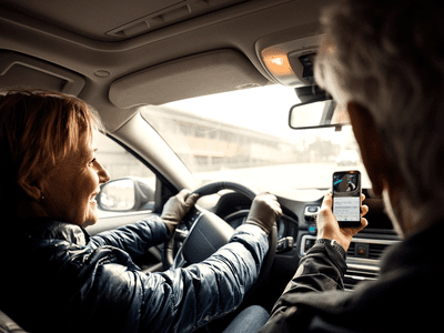 A passenger uses Visual Look Up on an iPhone to identify car symbols.