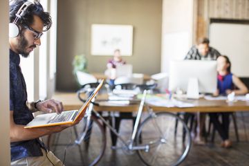 Person listening to music on laptop with bike in the background