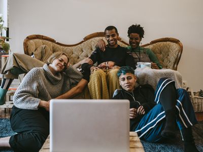 A group of people gathered around a laptop smiling