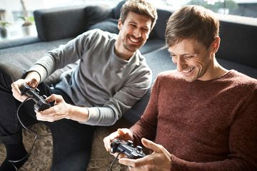 Two men playing an offline local multiplayer video game on their PlayStation 4 console.