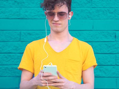 Skinny man in yellow t-shirt listening to bad music on his iPhone