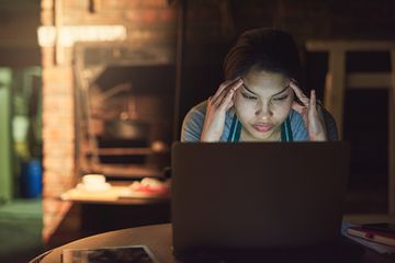 A woman with a frustrated facial expression is using a laptop computer