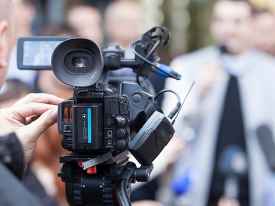 Photograph of man operating a professional video camera outdoors