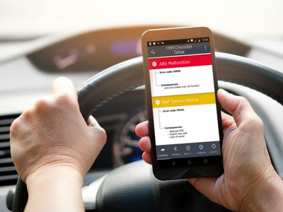 A man using Fixd on a phone to diagnose his vehicle in a car