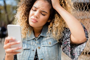 A person is looking frustrated while using a smartphone.