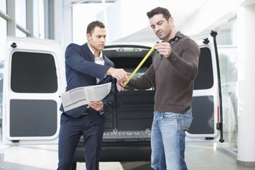 Two men in front of a van with a measuring tape