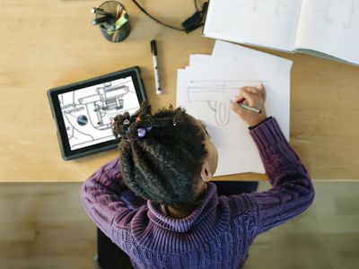 Child learning online with tablet and paper and pencil.