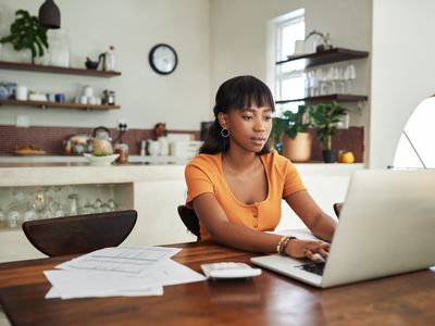 A woman using a laptop at a kitchen table