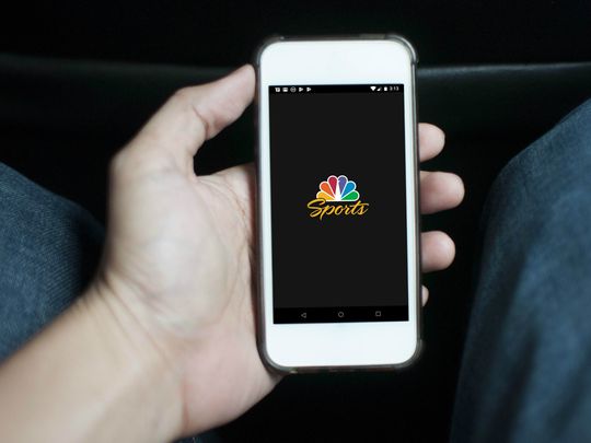 Someone holding a smartphone showing the NBC Sports logo