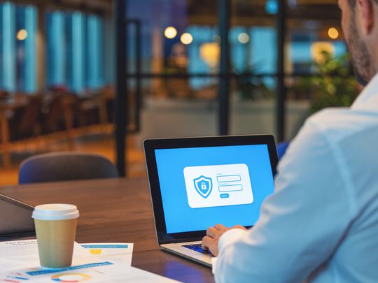 A businessman sitting in a cafe looking at an encryption lock on his Windows 11 laptop.