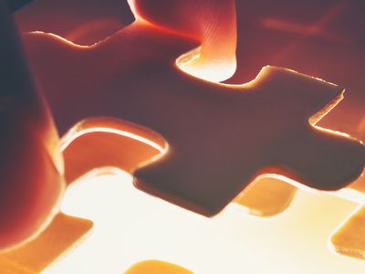 Closeup of a person placing a piece of a jigsaw puzzle down.