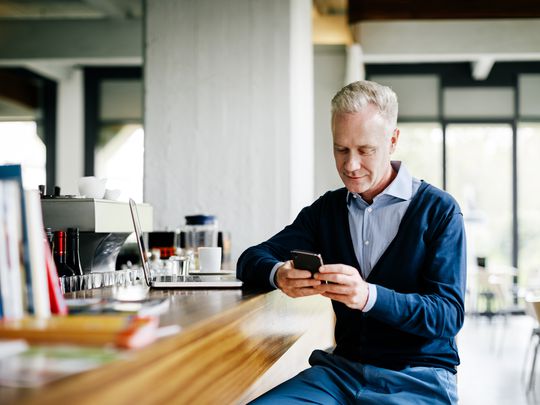 Man looking at his iPhone while sitting at a bar