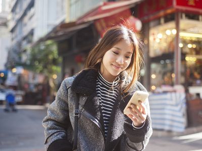 young person in fur jacket on the street looking at iPhone