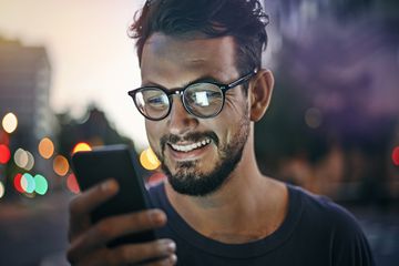 Smiling person with beard reading a text message.