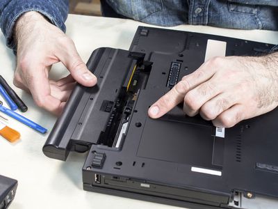 Photo of a technician removing a battery from a laptop.