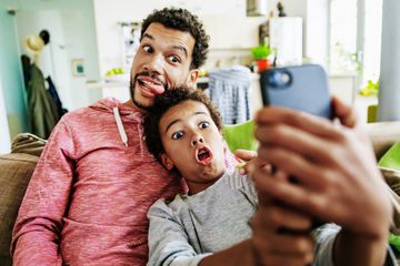 A father and son making funny faces while taking a selfie