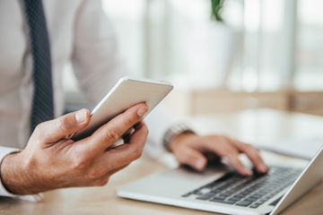 Person using iPhone and computer and a desk