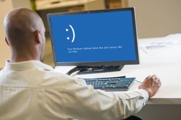 A man using a computer with the Windows Update failed message on the monitor.