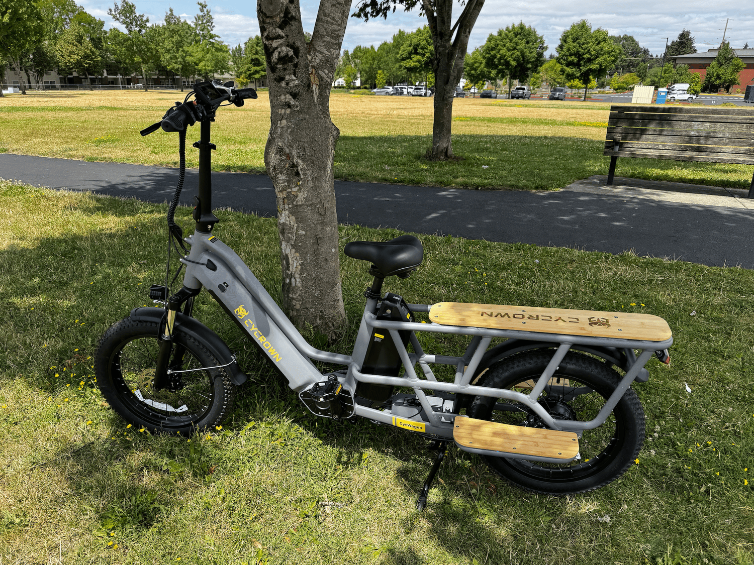 Cycrown CycWagon parked by a tree at a park in front of a park bench