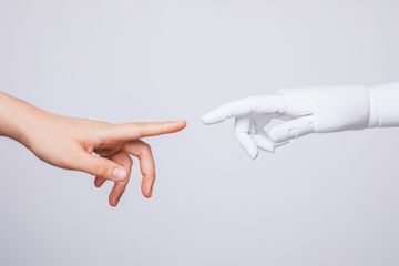 A human hand and a robot hand nearly touching fingers. 