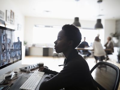 Female photo editor reviewing digital photo proofs on computer in office