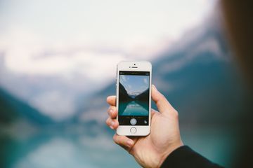 A person holding up an iPhone while taking a picture.