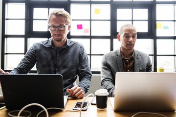 Two men working on laptops