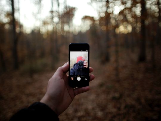 A photographer taking a selfie with an iPhone.