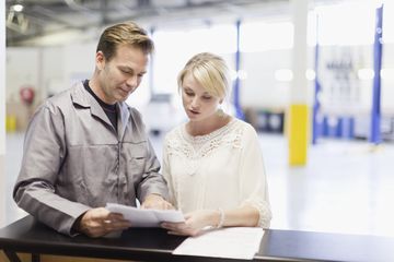 A technician helps a woman look up her car radio code.