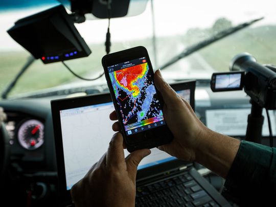 A storm chaser uses a radar app on his phone.