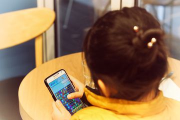 A kid playing Candy Crush on a Samsung phone.