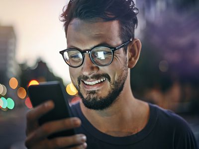 Smiling person with beard reading a text message.