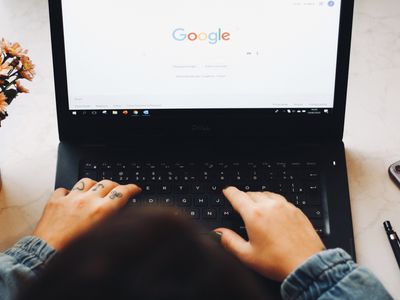 Someone with knuckle tattoos using Google Chrome on a black laptop