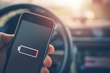 A hand holding a smartphone in a car